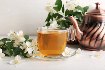 Glass cup of hot jasmine tea with flowers on white background