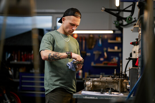 Mechanic repairing engine mechanism with tools in workshop garage