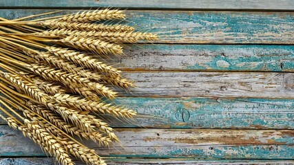 Golden wheat stalks arranged on rustic wooden planks, evoking a harvest theme with a serene backdrop