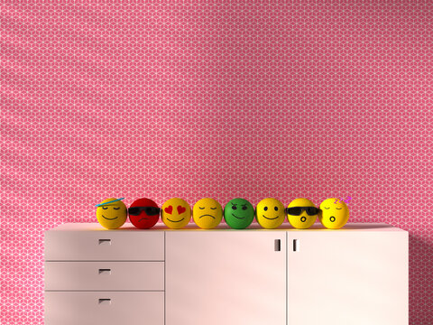 Knitted 3D emoji toys expressing emotions on cabinet against pink wall