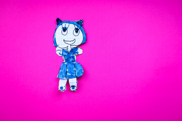 A cutout figure of a drawn girl-cat, colored blue, is placed on a rich pink background. The child's...
