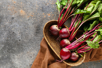 Wicker basket with fresh beetroots on grey grunge background