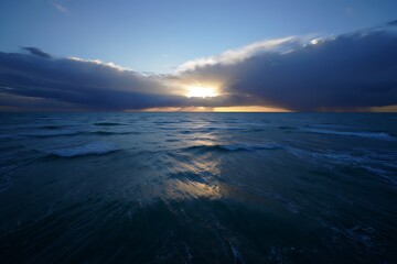 Obraz premium Dramatic sunset over the ocean with clouds and golden light reflection