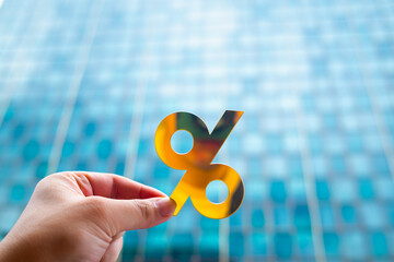 A businessman holds a golden percentage sign against a backdrop of large companies, showing how changing interest rates create problems that businesses must always manage.