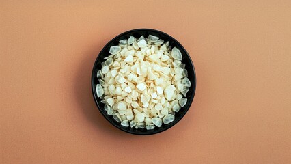 Konjac. Black bowl filled with white popcorn on beige background snack