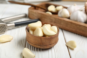 Bowl with fresh garlic cloves on white wooden background, closeup