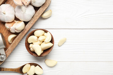 Tray with fresh garlics and bowl of cloves on white wooden background
