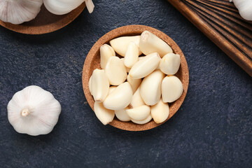 Bowl with fresh garlic cloves on dark background