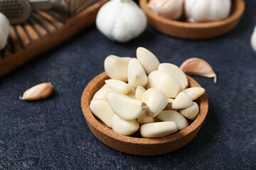 Bowl with fresh garlic cloves on dark background, closeup