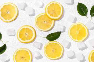 Slices of fresh ripe lemon with ice cubes and leaves on grey background