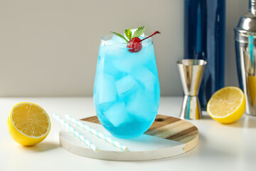 Glass of tasty Blue Lagoon cocktail garnished with cherry and lemon on white background