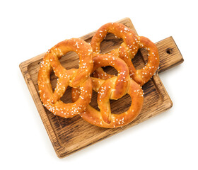 Wooden board with tasty salted pretzels on white background
