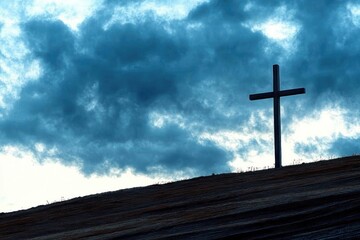 Solitary cross on hill against dramatic cloudy sky for spiritual reflection or meditation
