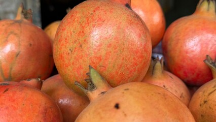 Close up on a pile of fresh pomegranates shows unique skin details clearly