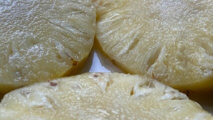 Close view shows yellow pineapple slices in a fresh arrangement sitting on a white surface