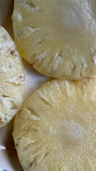 Closeup shows three pineapple slices, revealing juicy texture and light yellow color