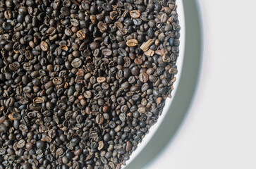 Green coffee beans in a white plate. Alternative drink concept. Selective focus. Horizontal orientation. Top view. Copy space