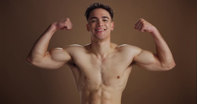 Muscles, flex and face of man in studio for health, fitness and strength on brown background. Bodybuilder, happy and portrait of person with biceps, growth and smile for confidence, pride or wellness