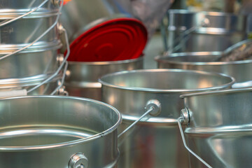 Rows of empty tin cans prepared for vibrant paint production. Empty vessels awaiting paint. Empty tin cans lined up in a paint factory. Rows of empty paint cans in an industrial setting.