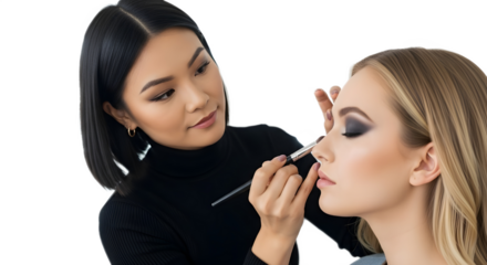 Professional makeup artist applying cosmetics to a beautiful client with a brush on a white background