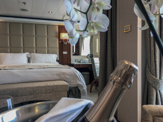 Luxurious suite stateroom cabin room onboard luxury all inclusive yacht cruise ship cruiseship liner with bedroom and living area in turquoise and creme with wood in modern Art Deco interior design