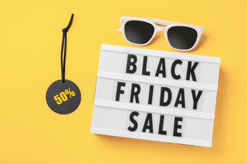 Black friday sale word on lightbox with sale tag and sunglasses on yellow background