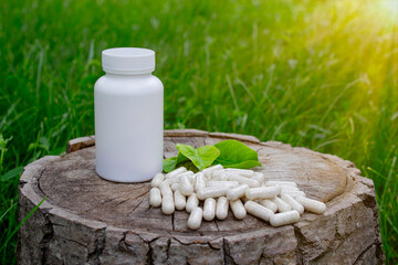 Herbal medicine in capsules with herb leaves on wooden stump.