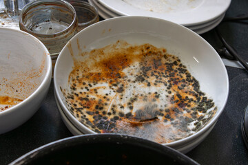Dirty dishes on a kitchen worktop with a mouldy bowl on a kitchen worktop.