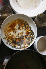 A mouldy bowl on a kitchen worktop with dirty plates and pans.