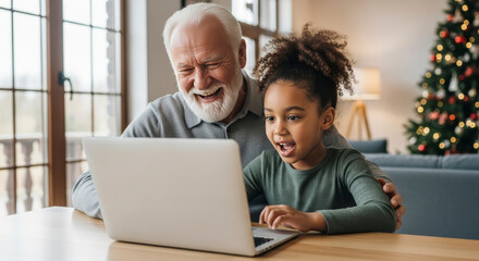 A joyful grandfather and his happy granddaughter are actively engaged in watching content on a laptop at home during the holiday season