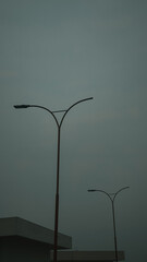 Minimalist streetlights with elegant curved arms silhouetted against a moody, overcast sky—perfect for urban design, architecture, and modern cityscape stock photography