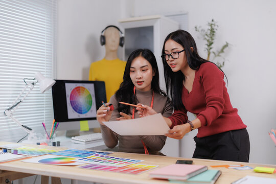 Fashion designers discussing sketches and color palettes in creative studio