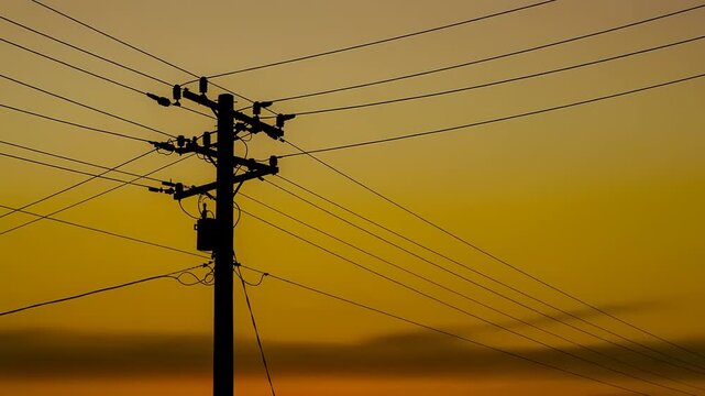 Silhouette of utility pole and wires at sunset