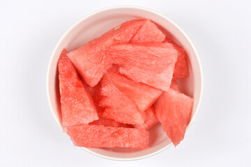 A white bowl, filled with vibrant red watermelon pieces, is centered on a clean white background, inviting a refreshing bite
