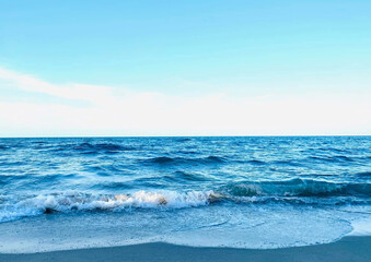 Deep blue sea view with waves gently crashing onto the sandy shore, capturing the serene beauty of a coastal paradise.