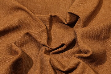 Brown fabric background. Selective focus. Brown cloth waves background texture.