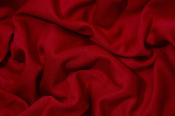 Red fabric background. Selective focus. Red cloth waves background texture.