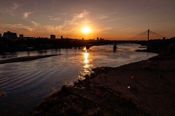 Fototapeta premium sunset over the river with city and bridge in the background
