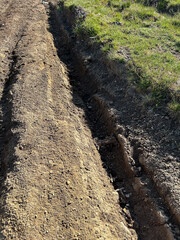 Freshly dug trench in a grassy field
