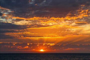 Dramatic ocean sunset with golden rays and glowing clouds, Australia