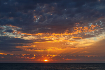 Dramatic ocean sunset with golden rays and glowing clouds, Australia