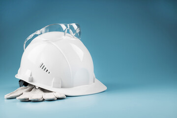 White construction worker safety helmet with personal protective equipment on blue background