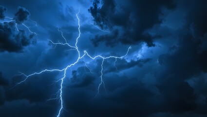 Thunderstorm lightning flash illuminating stormy clouds in electric blue night sky with atmospheric moody background for weather and energy concept images