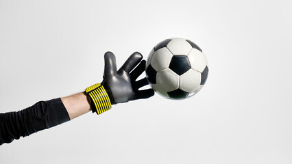 Goalkeeper reaching toward flying soccer ball in mid-air. Concept of football technique, goalkeeping posters, reflex training, sports lifestyle promo, save motion, agility visuals.