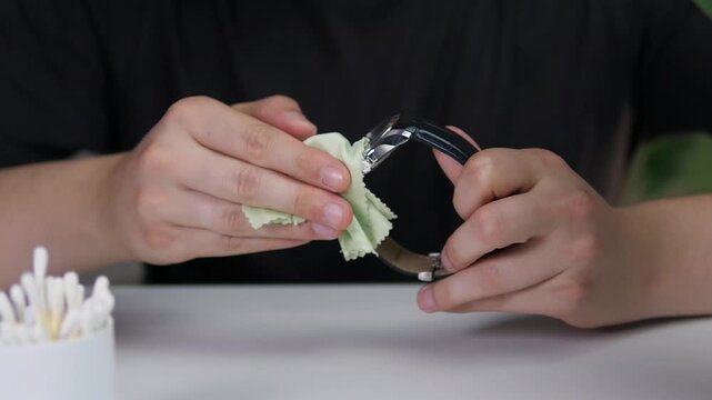  A Close-up of a man's hands wiping a leather strap wristwatch with a special cloth. Expensive wristwatches that convey status. 