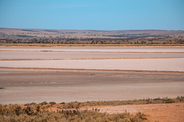 Pink salt crust and dry textured surface of Lake Bumbunga under blue sky, South Australia