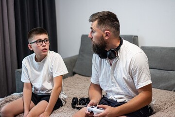 A father and son have a conversation while the father holds a video game controller.