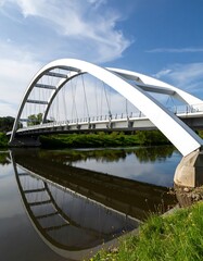 Obraz premium Modern white arch bridge over calm river