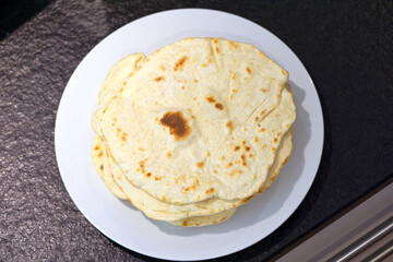 High angle view of naan on white plate against black stone background. Photo taken June 1st, 2025, Zurich, Switzerland.