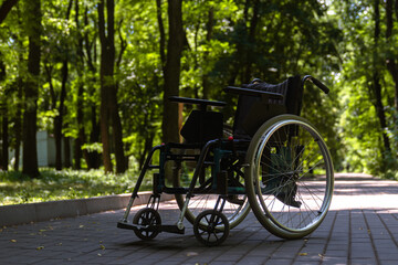 Obraz premium Empty Wheelchair Parked on a Sunlit Path in the Woods
